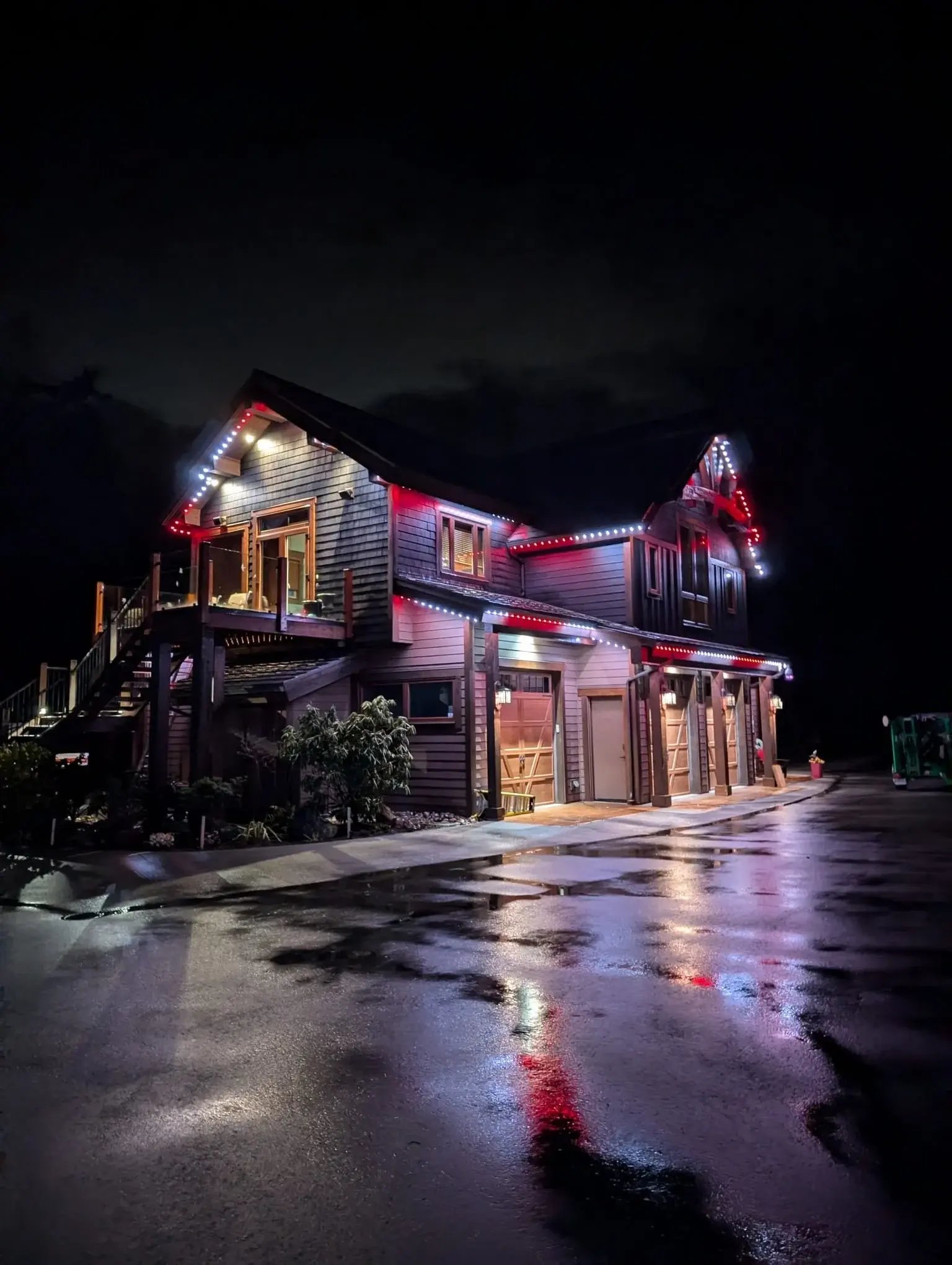 Home illuminated with red and white permanent outdoor lighting at night