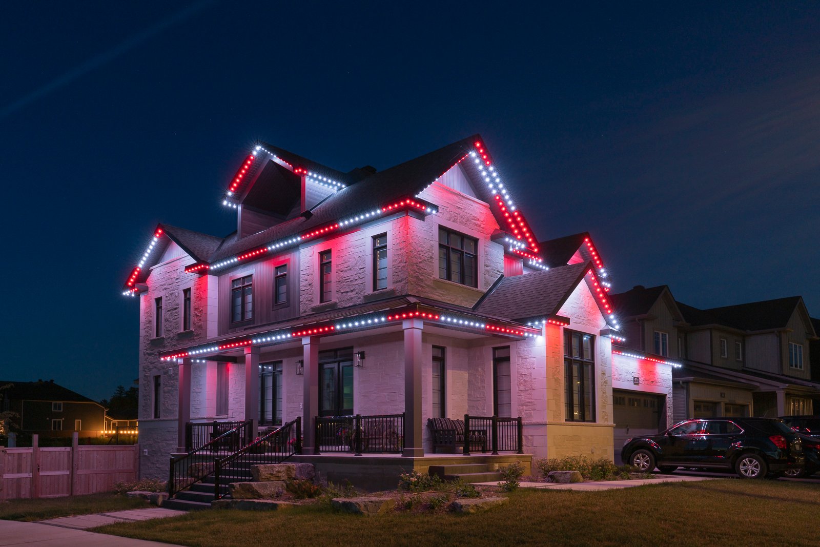 Residential home illuminated with permanent Christmas lighting in red and white