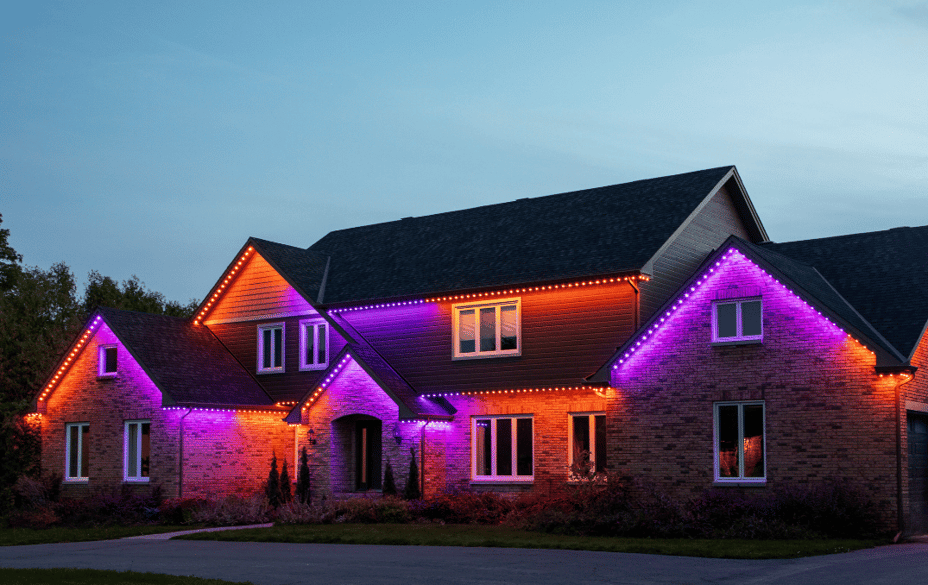 Large two-storey home illuminated with orange and purple Permanent Outdoor Lighting for a bold Halloween display.
