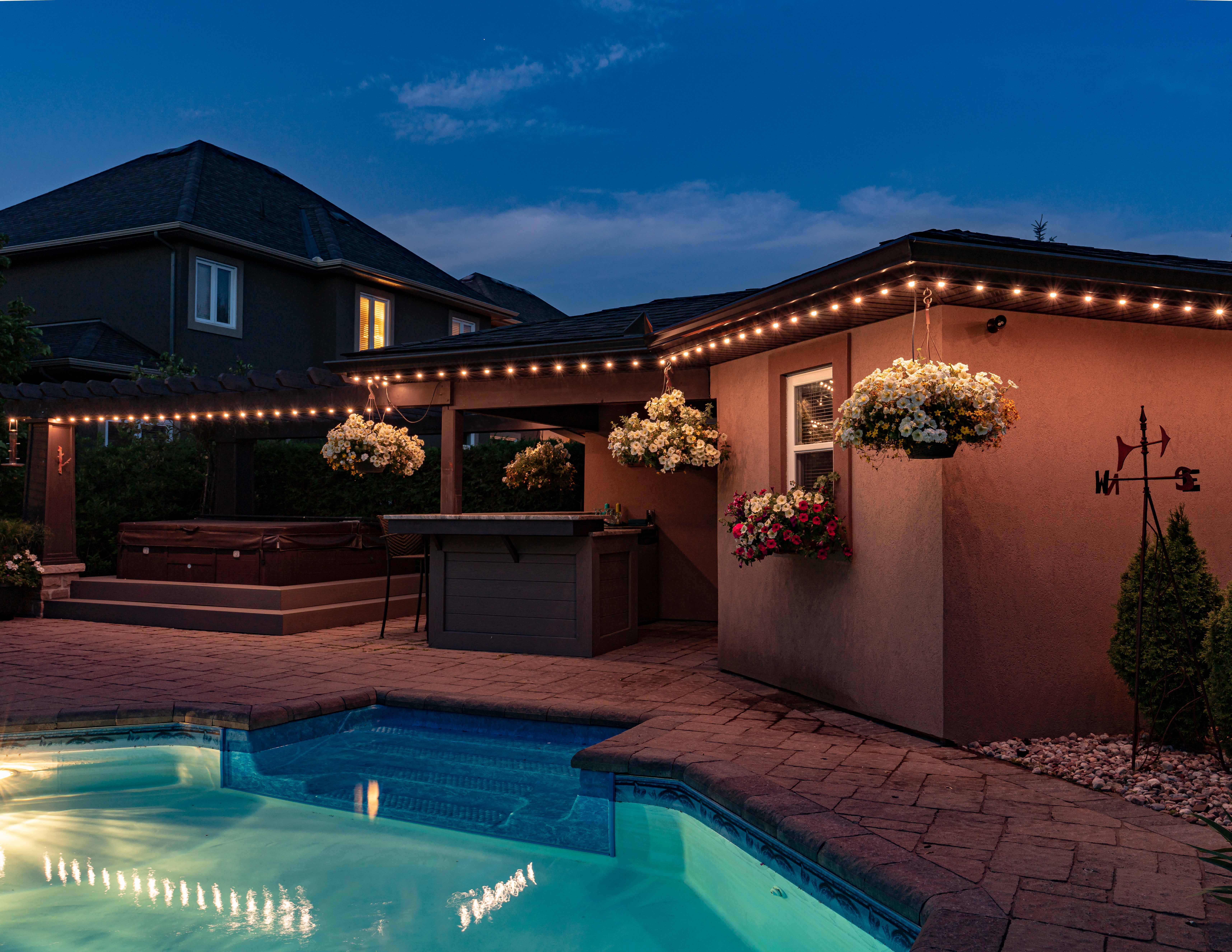 Backyard patio with permanent outdoor lighting, pool, and bar area creating a cozy ambiance