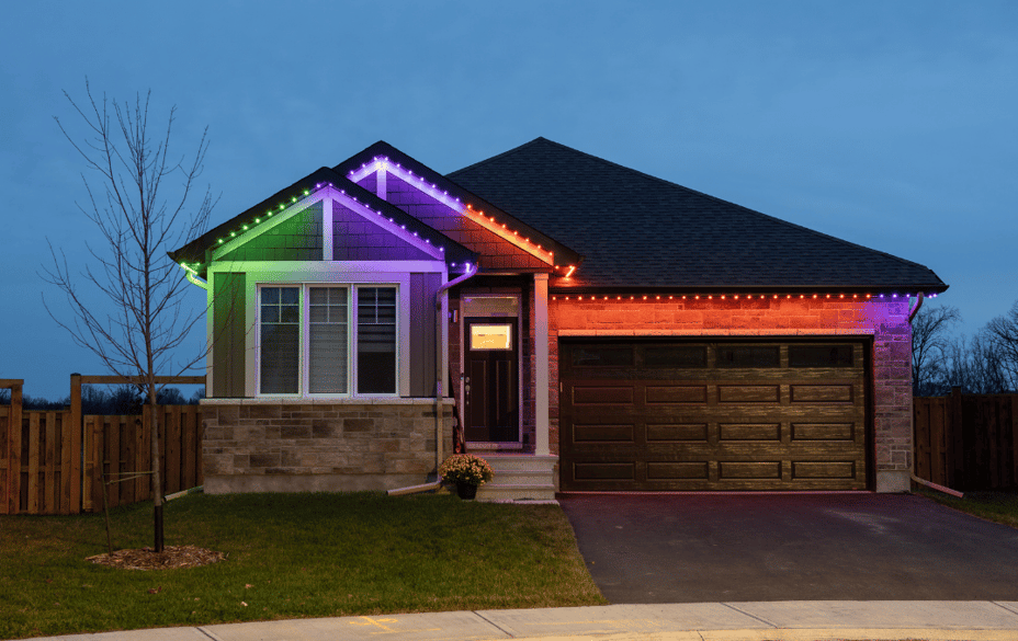 Single-storey home illuminated with green, purple, and orange Permanent Outdoor Lighting for a colorful Halloween display.