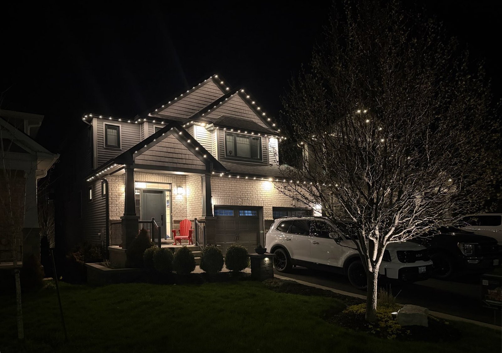 Permanent holiday lighting installed along the roofline of a modern two-story home, providing elegant year-round outdoor illumination.