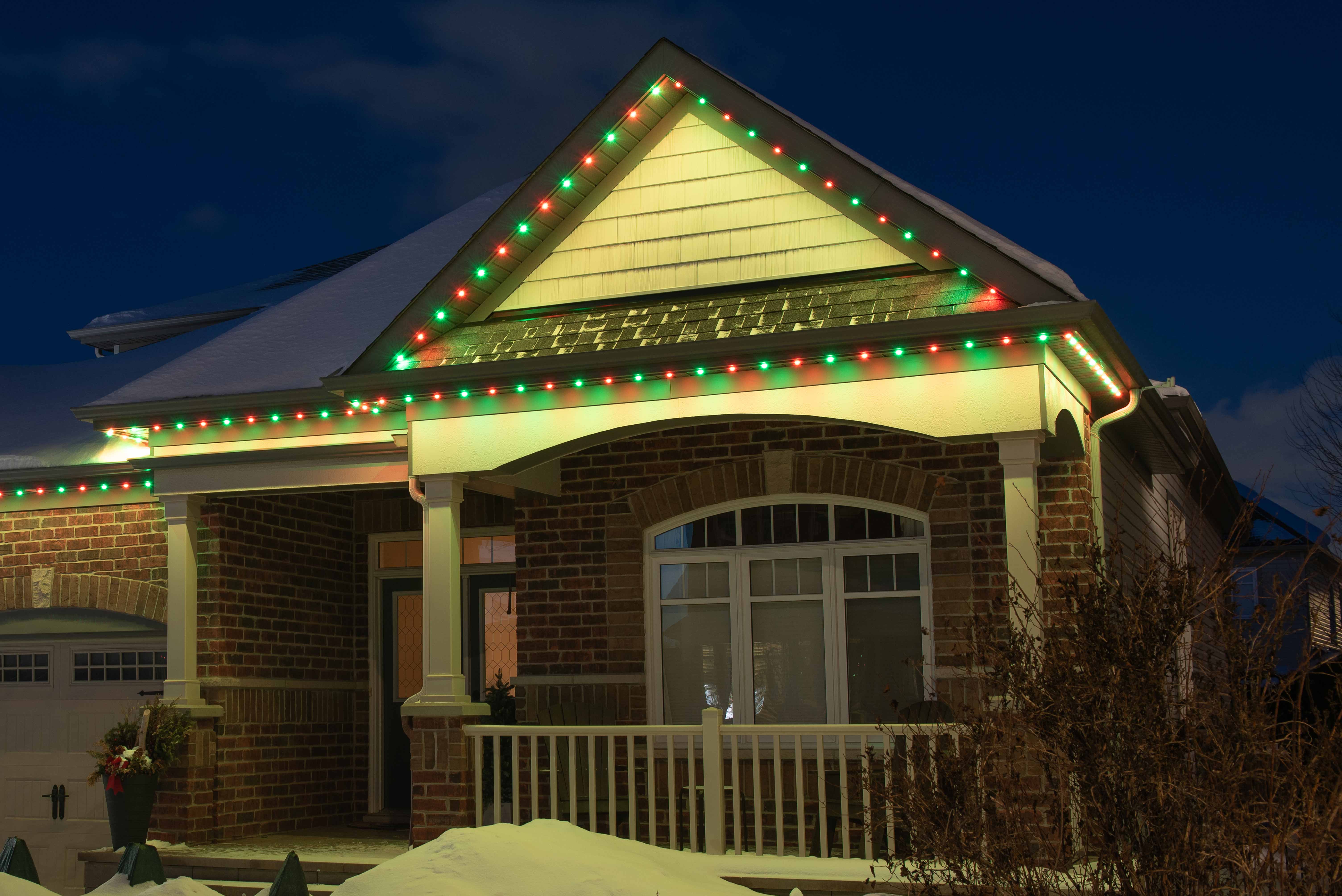 House at night with Celebright permanent lights showing the Holly Berry preset.