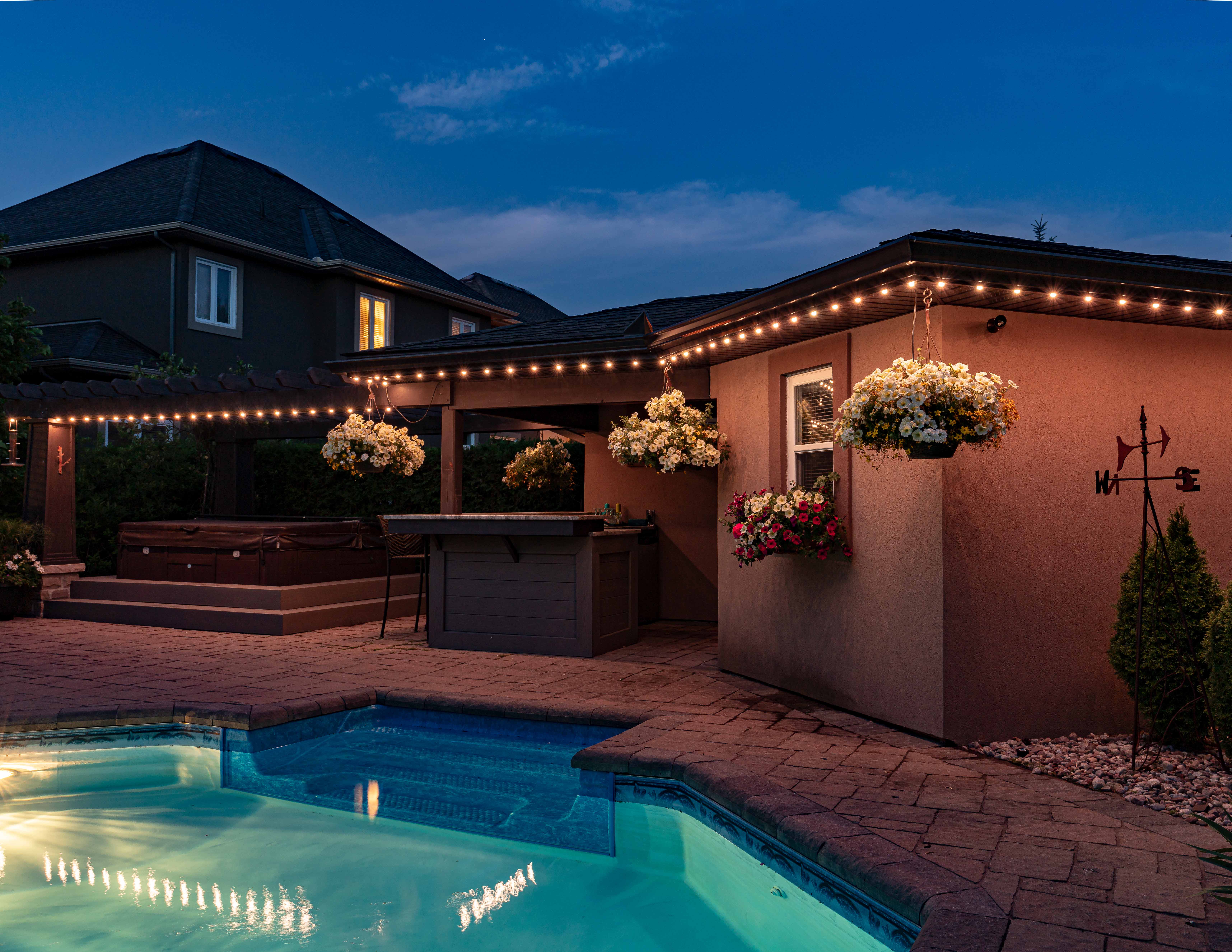 Backyard patio with permanent outdoor lighting, pool, and bar area creating a cozy ambiance