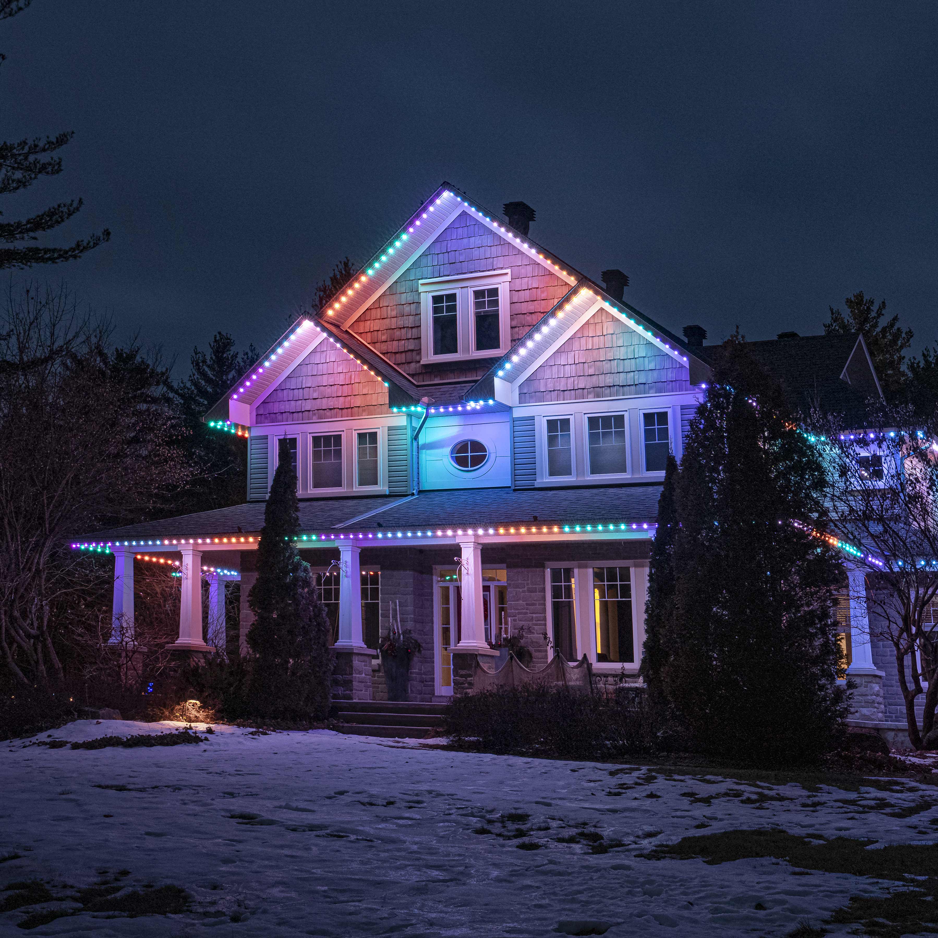 House outlined with red and white permanent Christmas lights glowing at night.