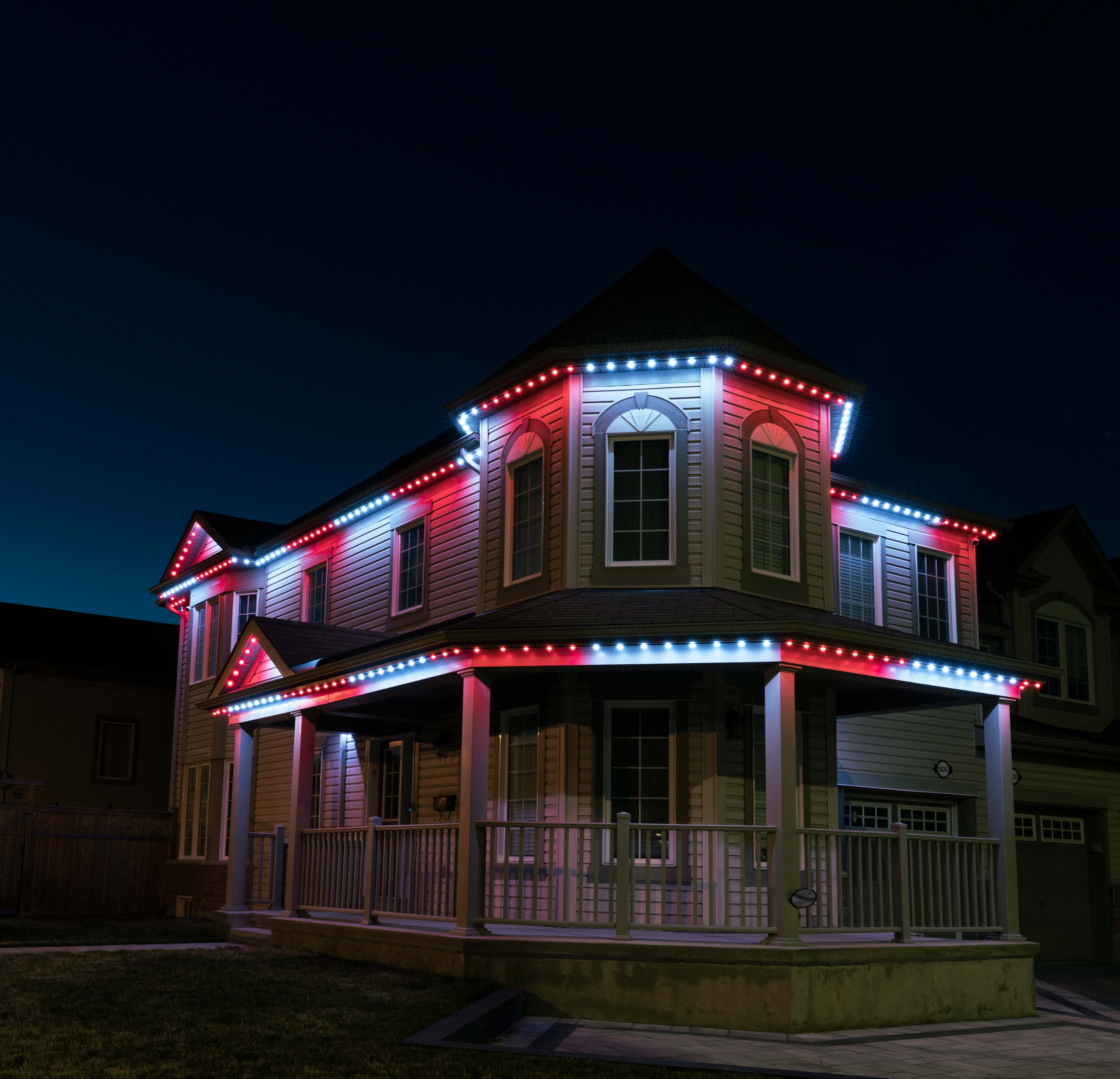 House outlined with red and white permanent Christmas lights glowing at night.