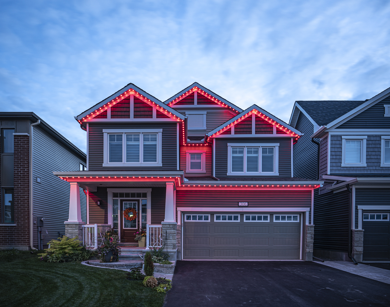 House glowing with festive red permanent Christmas lights at dusk.
