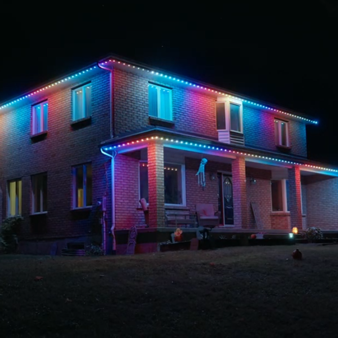 House outlined with red and white permanent Christmas lights glowing at night.