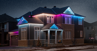 Colorful permanent Christmas lights illuminating a house in a snowy, festive Christmas setting.