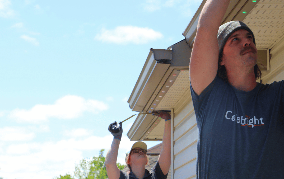 Celebright installers mounting permanent holiday lights along a home’s roofline.