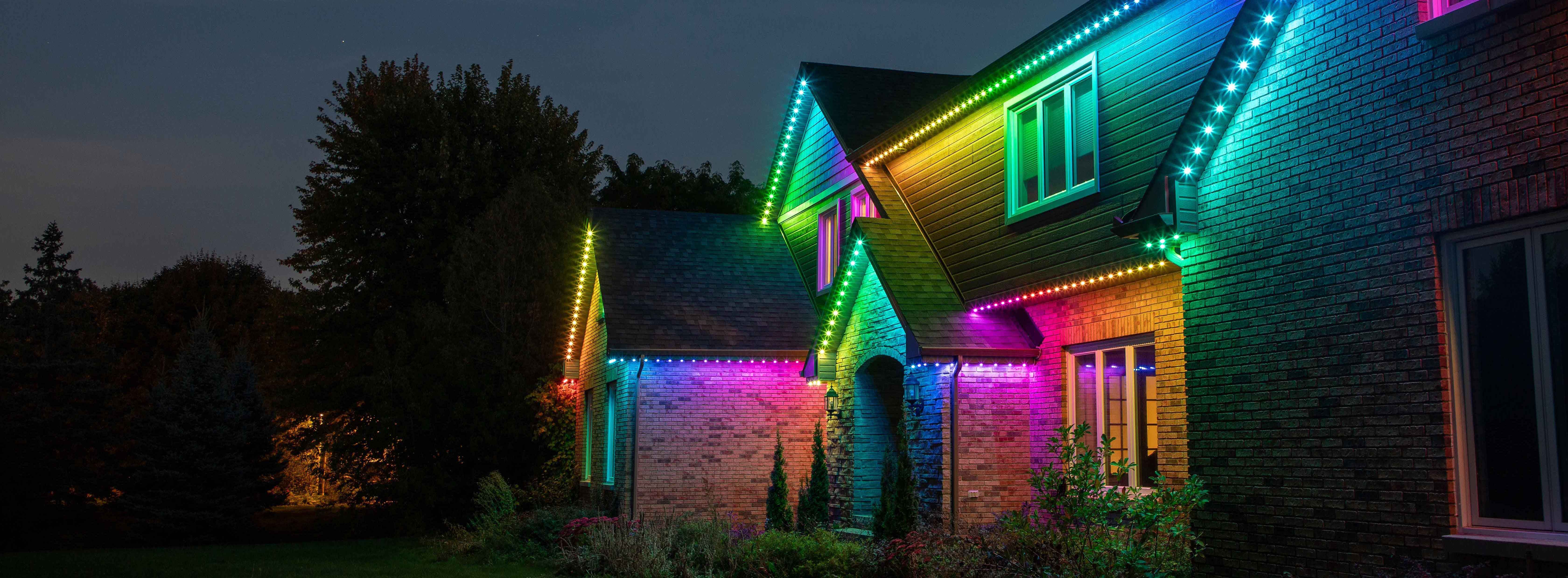 Permanent Holiday lighting displaying colorful LED lights along a home’s roofline at night.