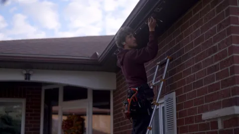 Celebright installer setting up permanent holiday lights along the roofline of a house